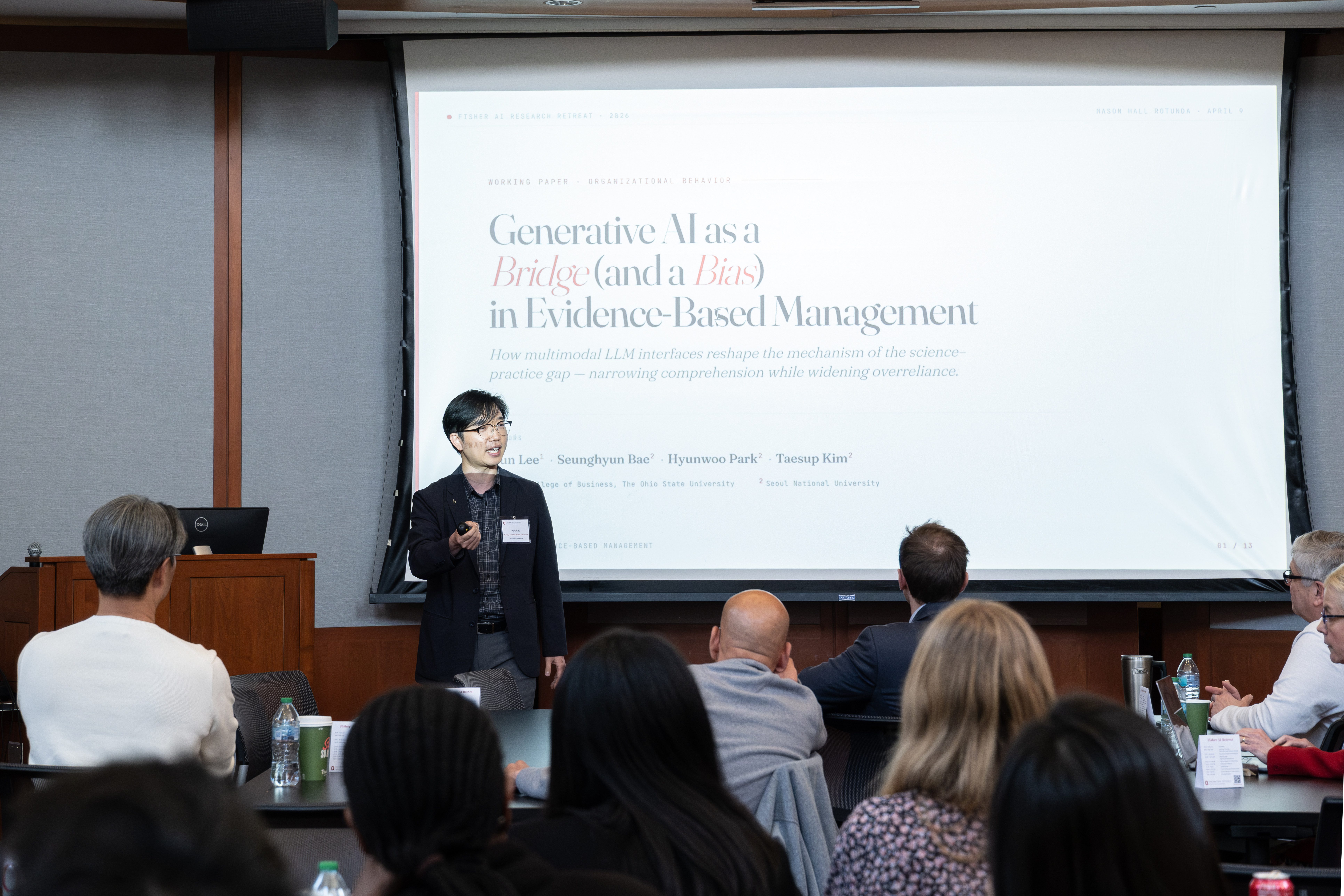 Hun Lee in suit in front of screen in small meeting room explaining his research