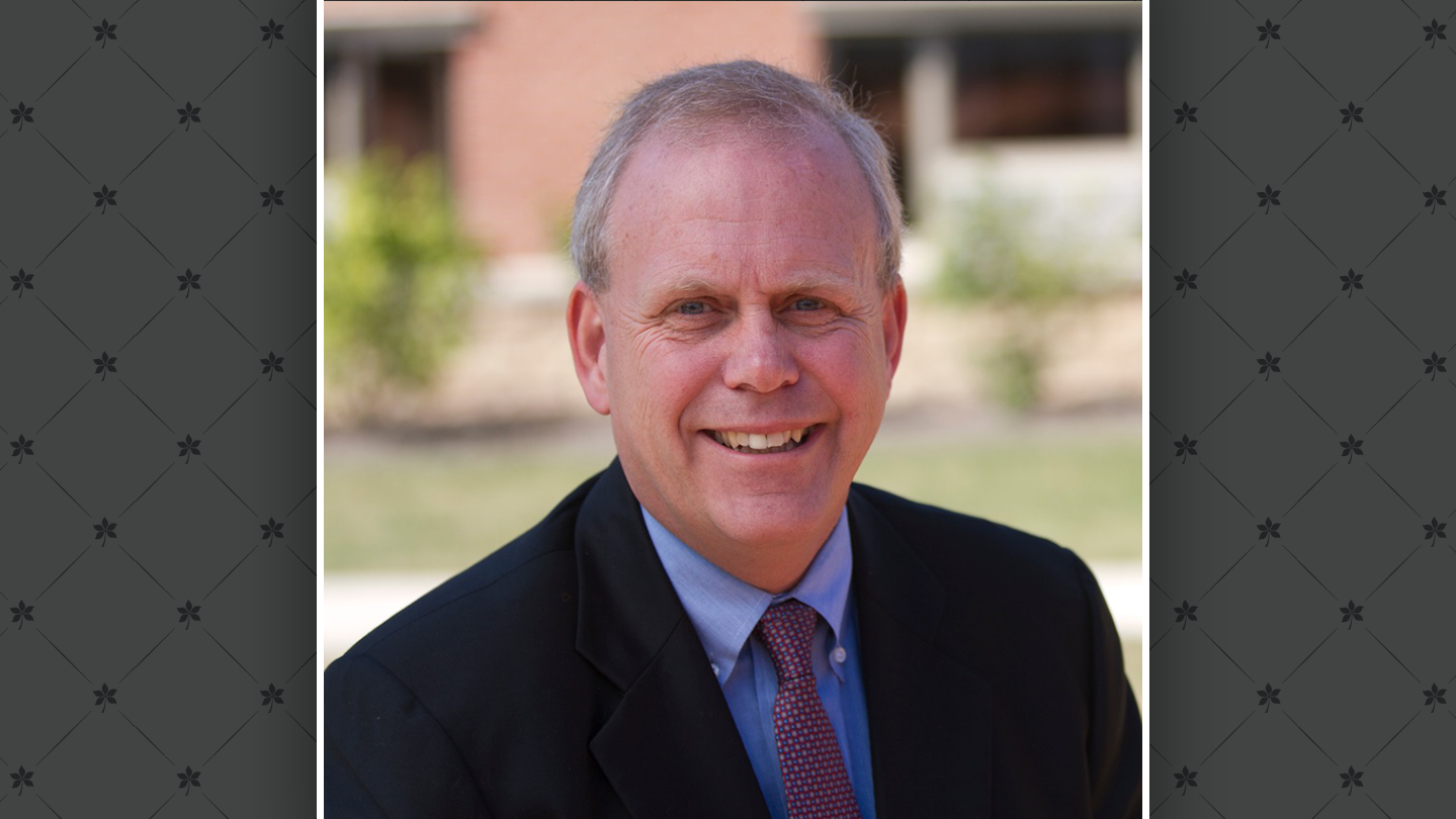 A headshot of Greg Allenby laid on top of a gray graphic of buckeye leaves.