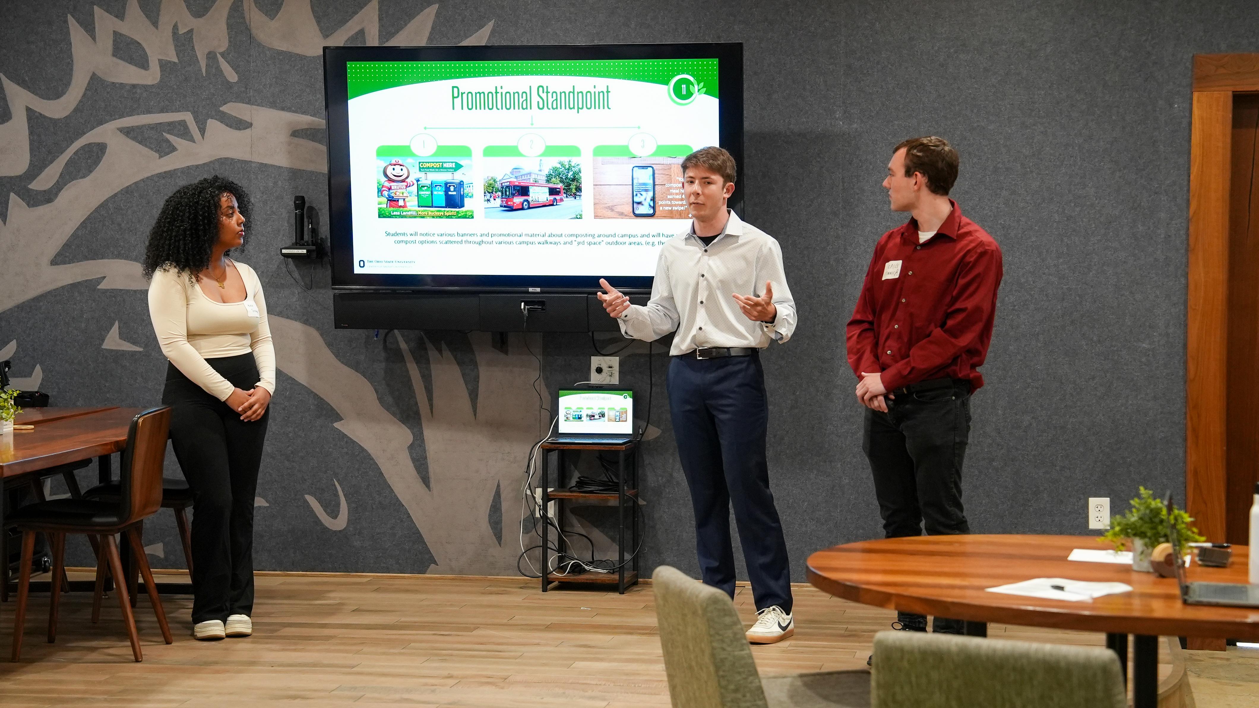 Students present in front of a digital display.