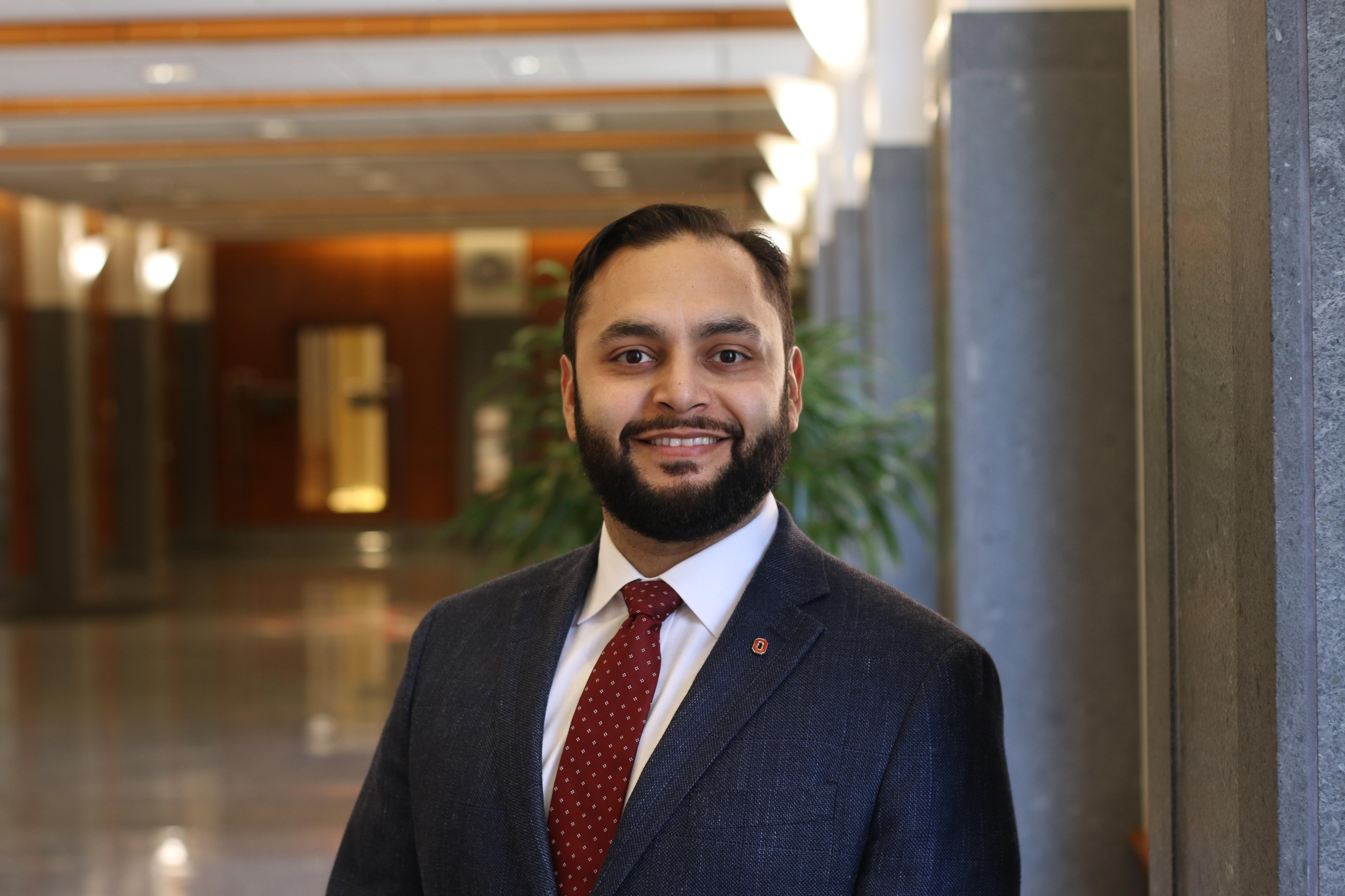 Vince Castillo in a dark suit and red tie.