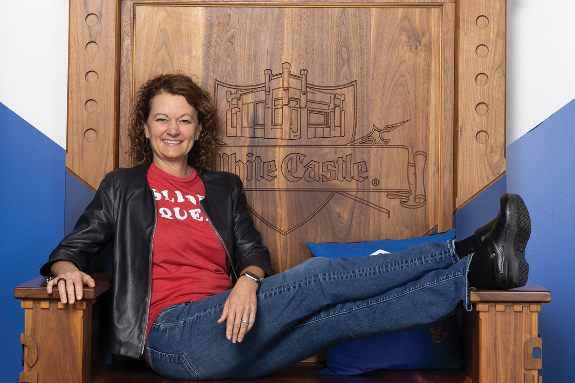 Lisa Ingram reclines on a large wooden throne-style chair with the White Castle logo engraved on the backrest.