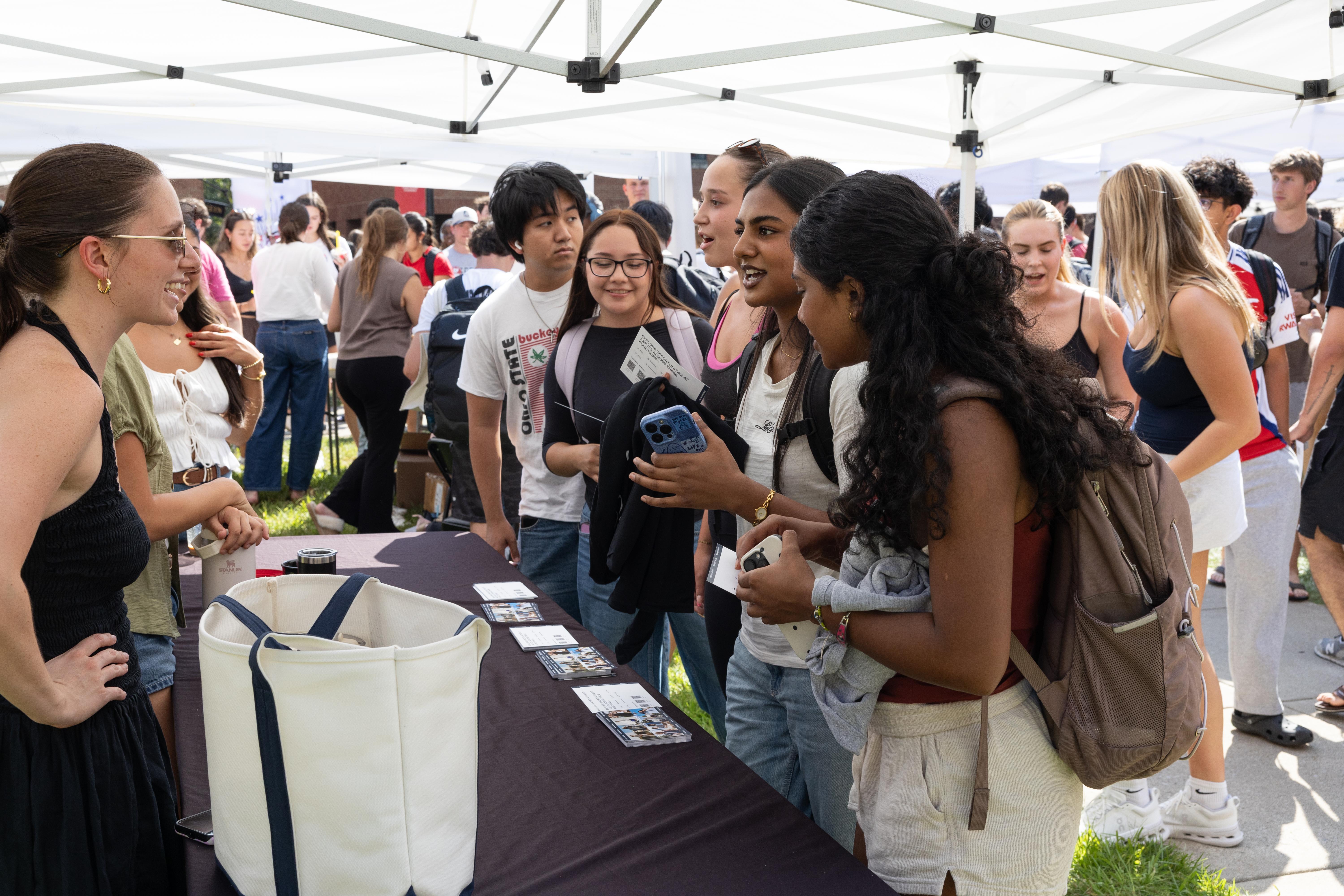 Group of students gathered around table under a tent