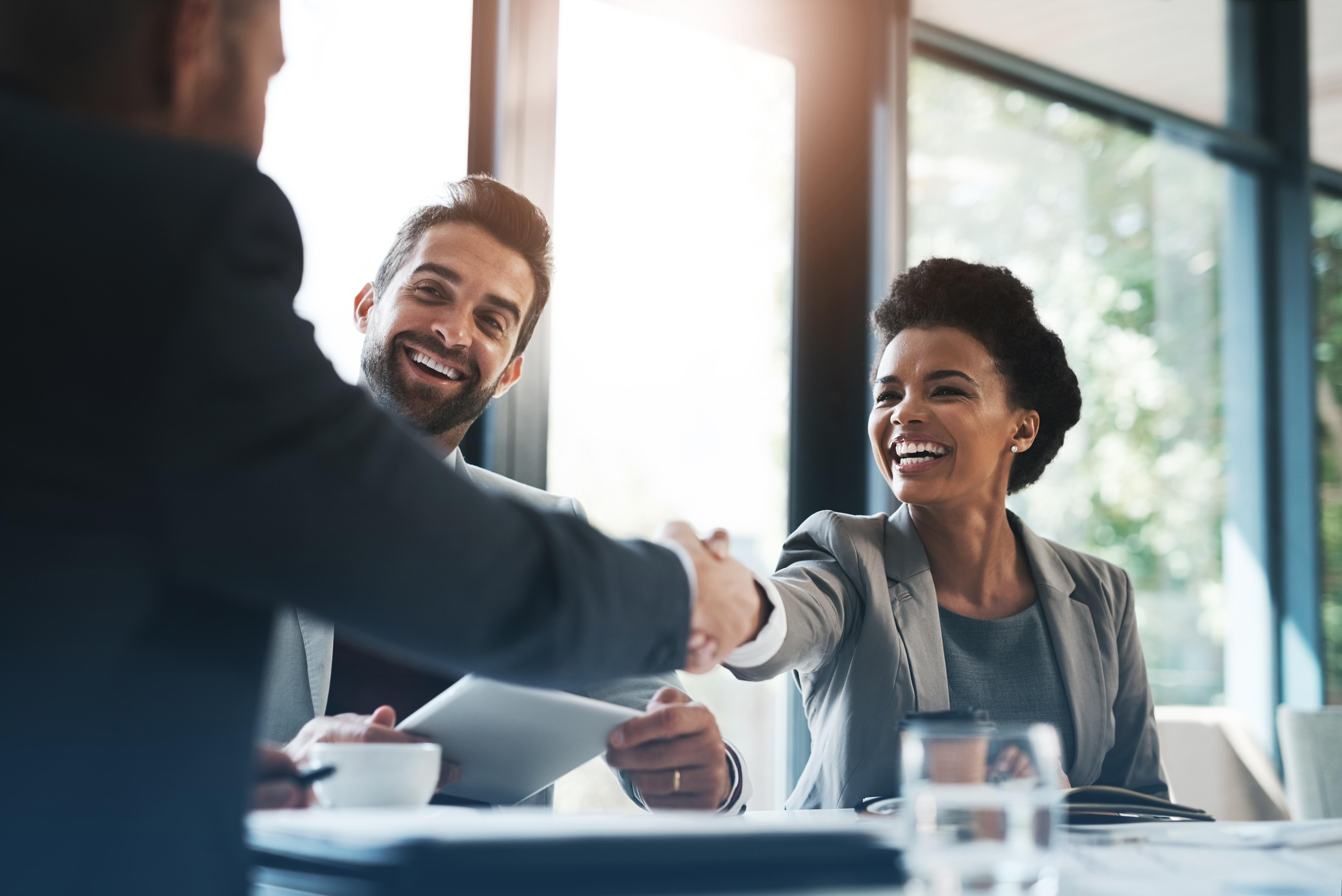 Man shaking hands with woman while another man looks on