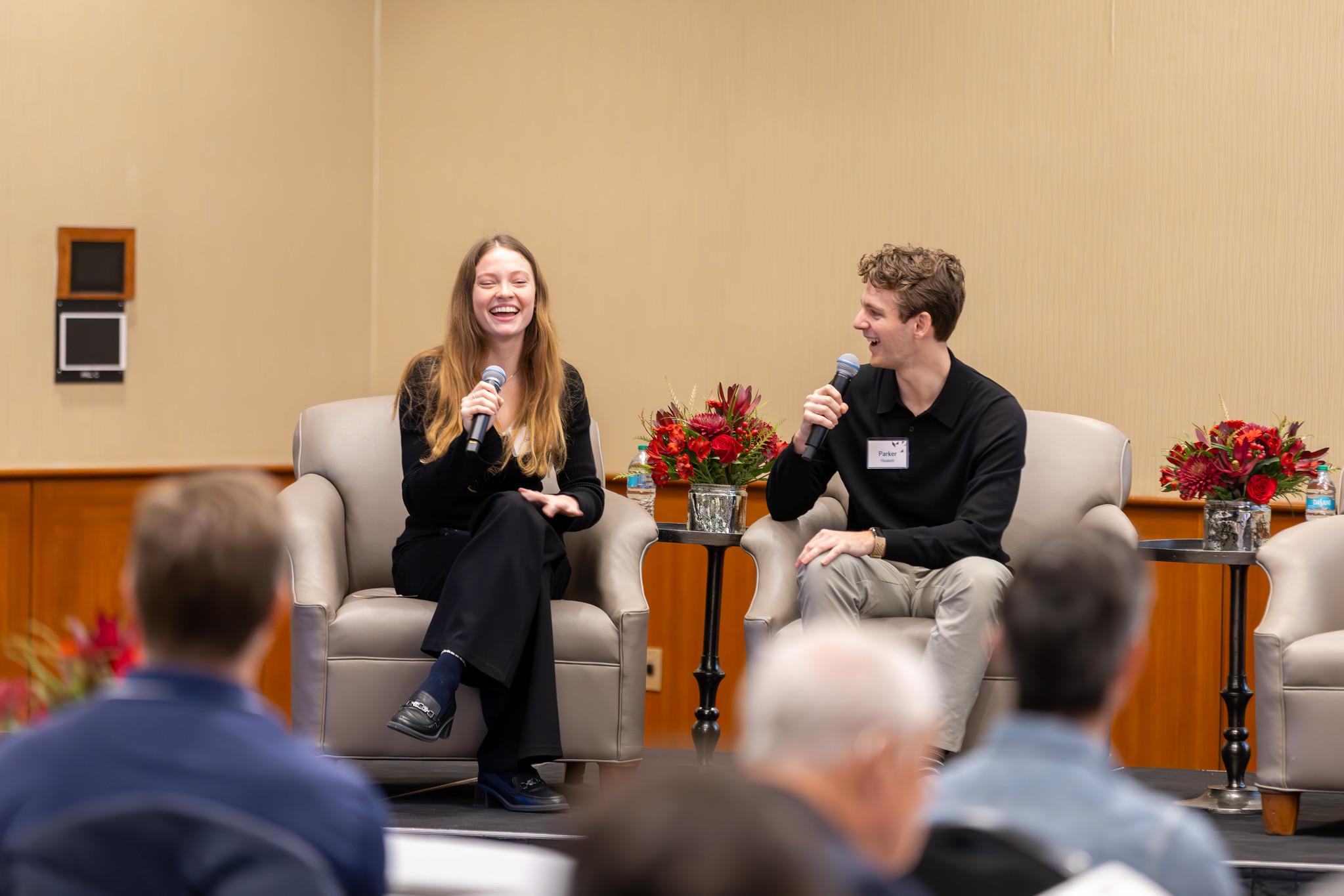A female and male speaker laugh during their presentation at the Wolstein Summit.