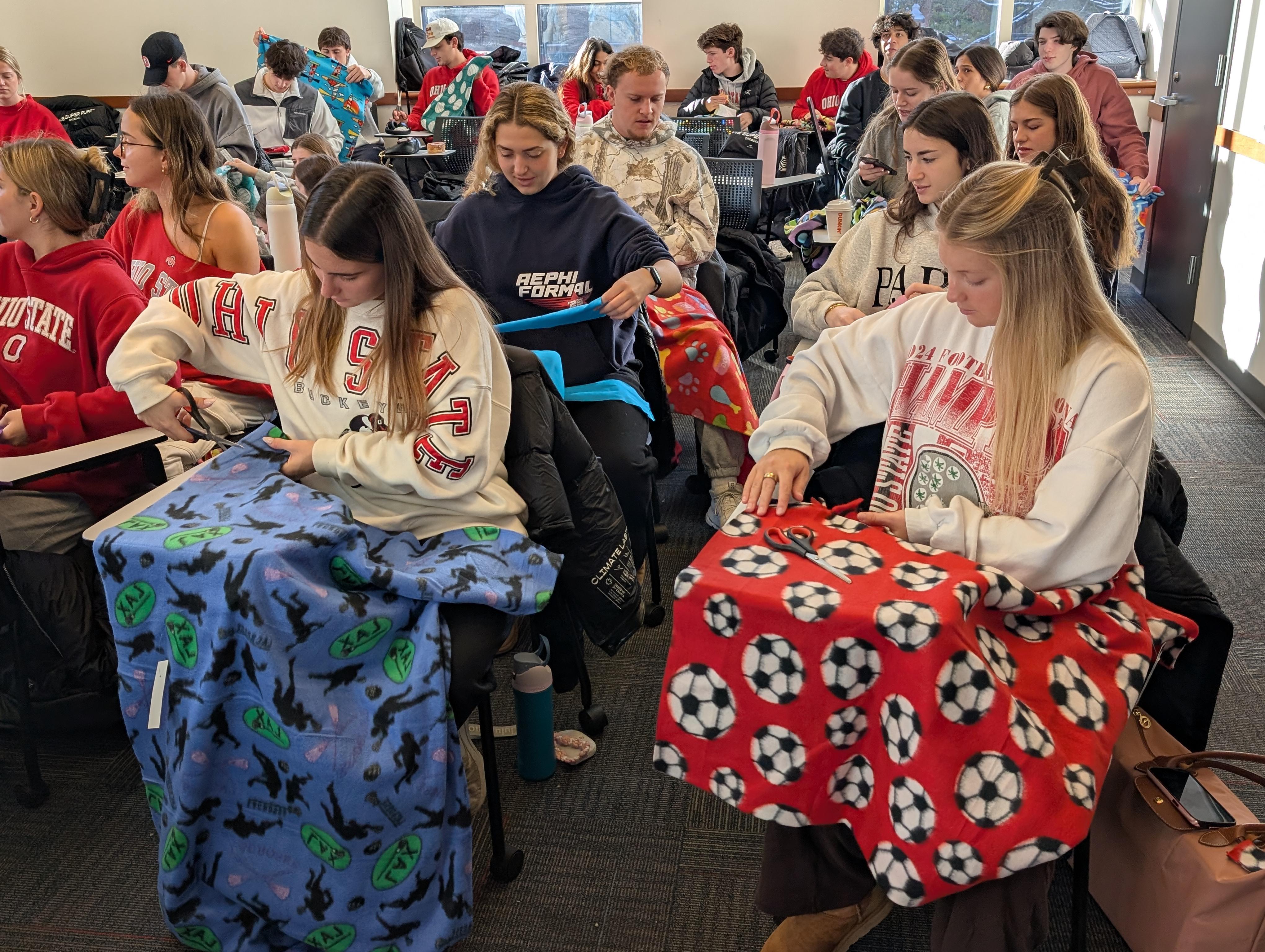 Group of students creating no sew flannel fleece blankets