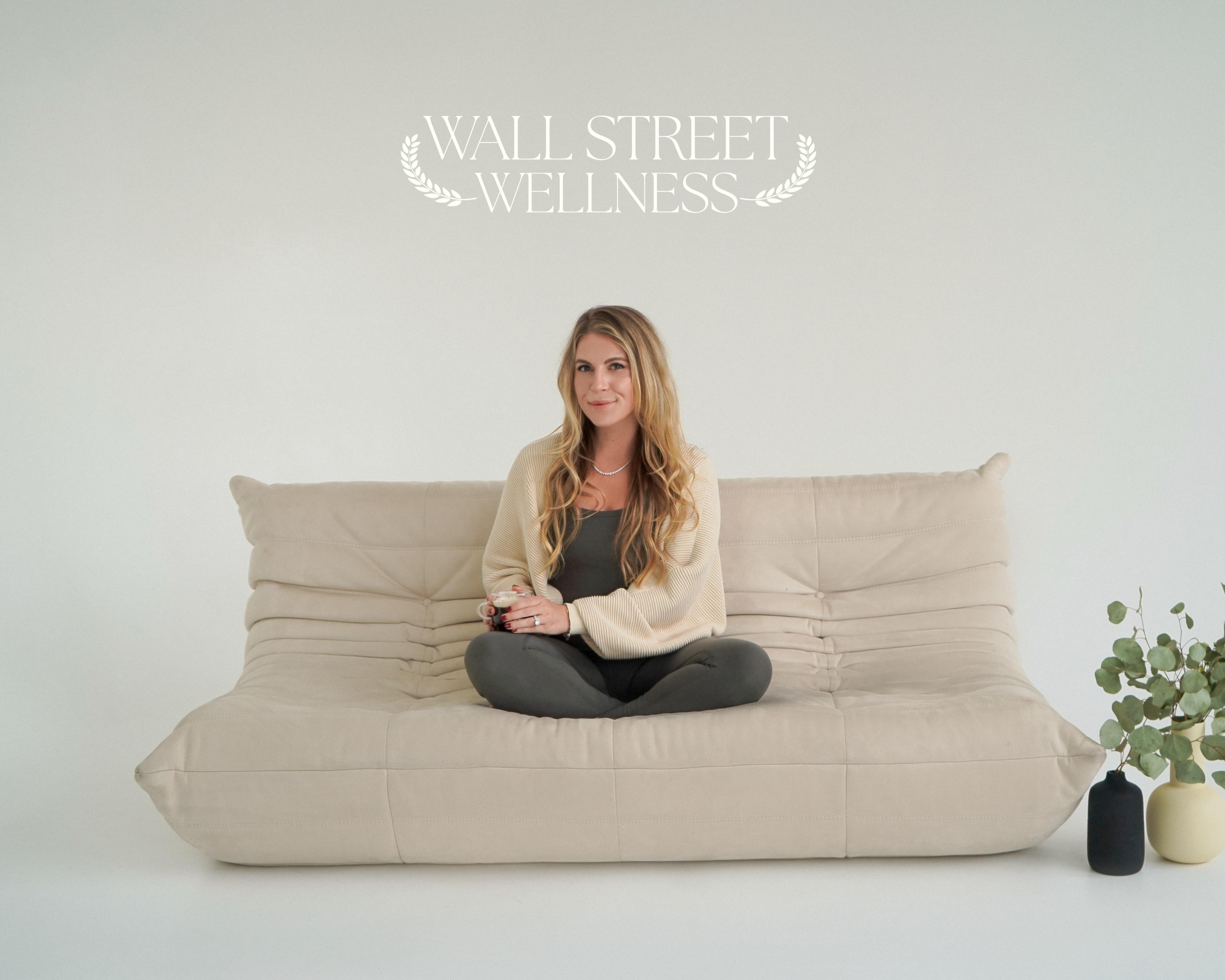 Sophia Mullins is seated on a tan fouton against a cream backgound