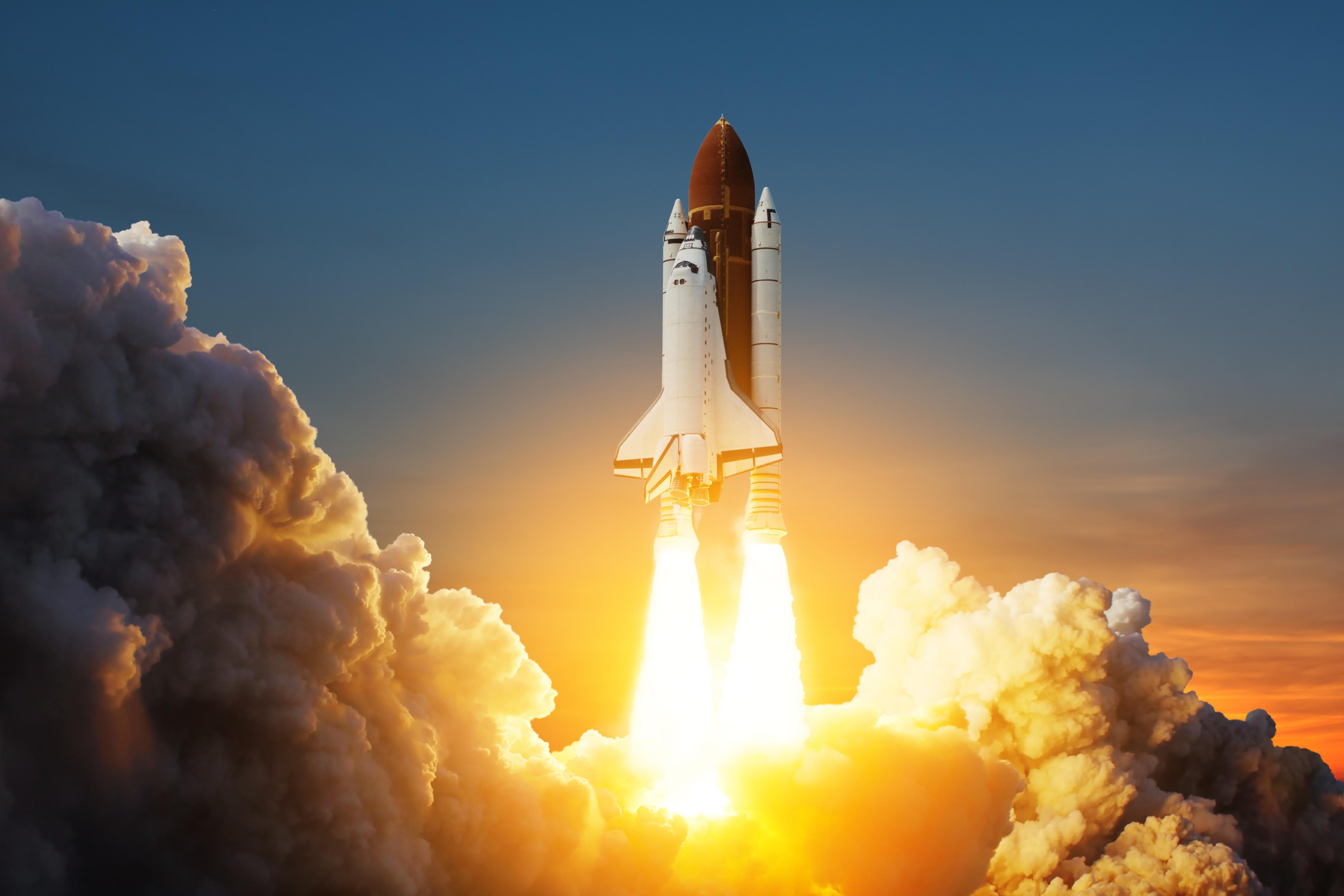 Space shuttle taking off with fire spewing out of jets creating clouds of smoke