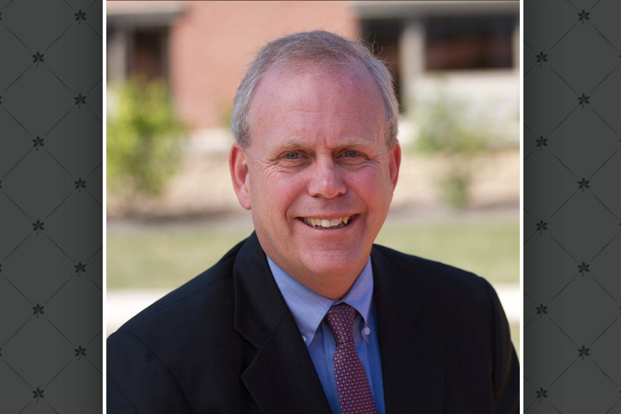 A headshot of Greg Allenby laid on top of a gray graphic of buckeye leaves.