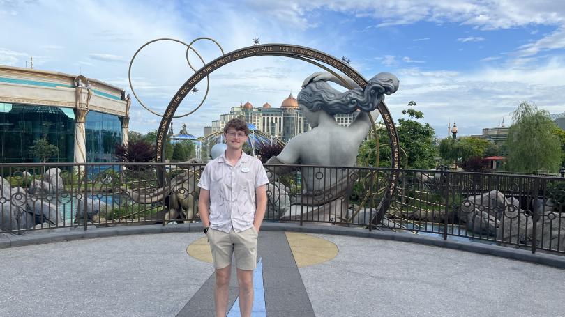 Tyler DiFranco in shorts with oversized sculpture of person with flowing hair and arch in the Court of the Moon in Celestial Park
