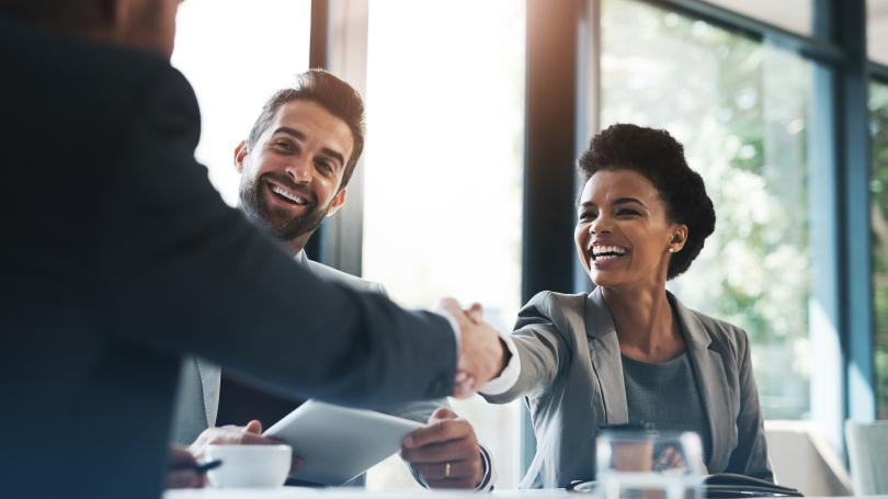 Man shaking hands with woman while another man looks on