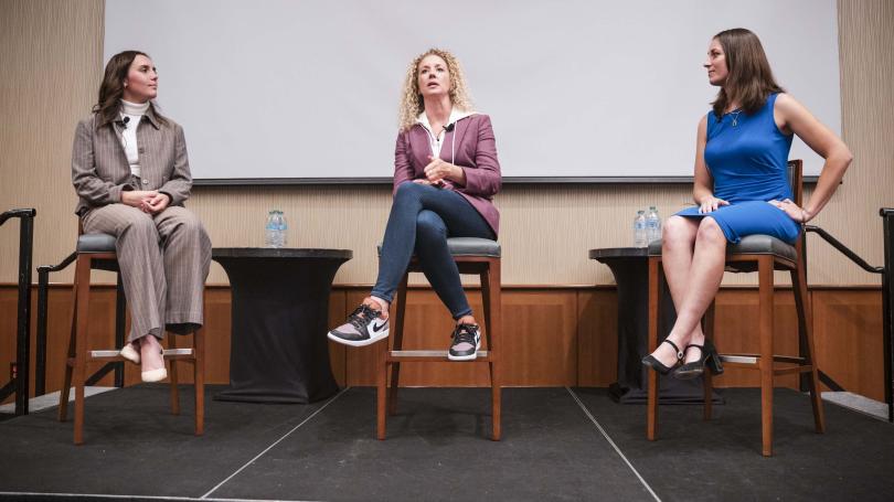 Becky Griffin seated on stage with students Marlie Moner and Chantel Fucci