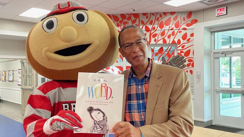 Dwight and Brutus Buckeye are holding up a book titled My Special Word.