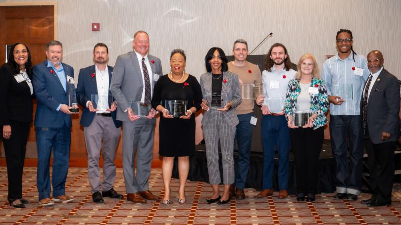 Community Impact Award honorees pose together holding their glass awards.