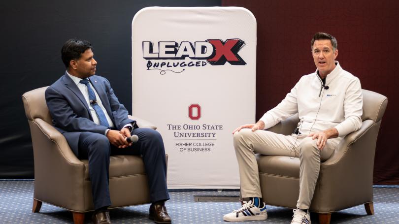 Dean Aravind Chandrasekaran and Geoff Gilmore sitting opposite each other with LeadX sign in background