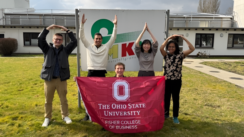 Student holding Ohio State banner, while four students spell out O-H-I-O in front of a sign saying MKV