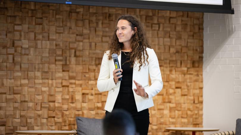 Amani McKavish-Kimball in white jacket holding microphone while giving presentation at Rockbridge