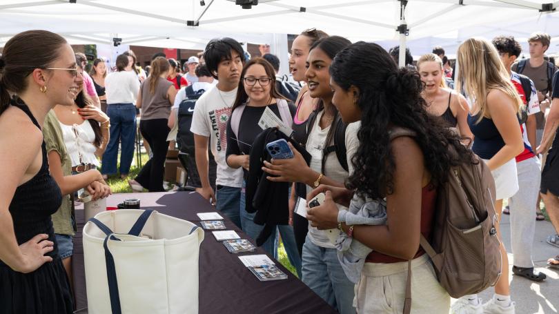 Group of students gathered around table under a tent