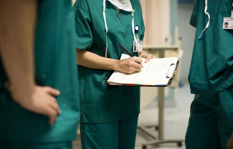 Stock image of a doctor in scrubs holding a medical chart