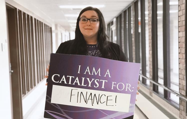 Dignity Ruebensaal holding a sign that reads "I am a catalyst for finance!"