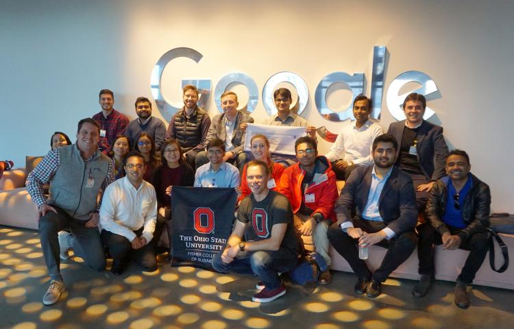 Group of MBA students display block O sign in front of Google logo