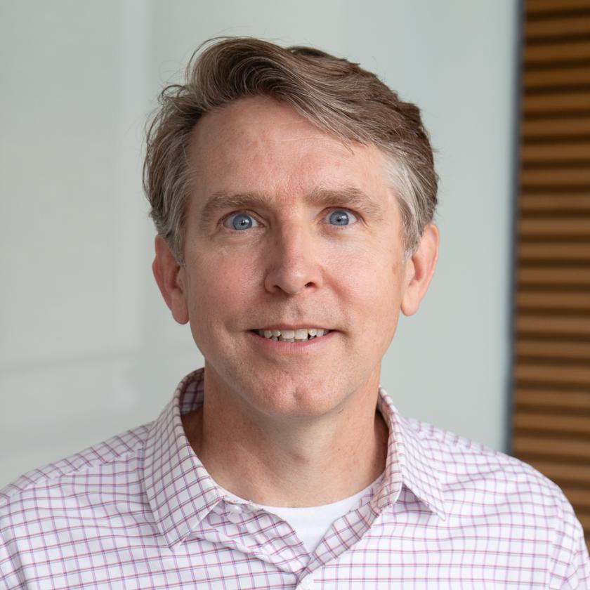 Brian Mittendorf, smiling, wearing a red and white checkered collared dress shirt 