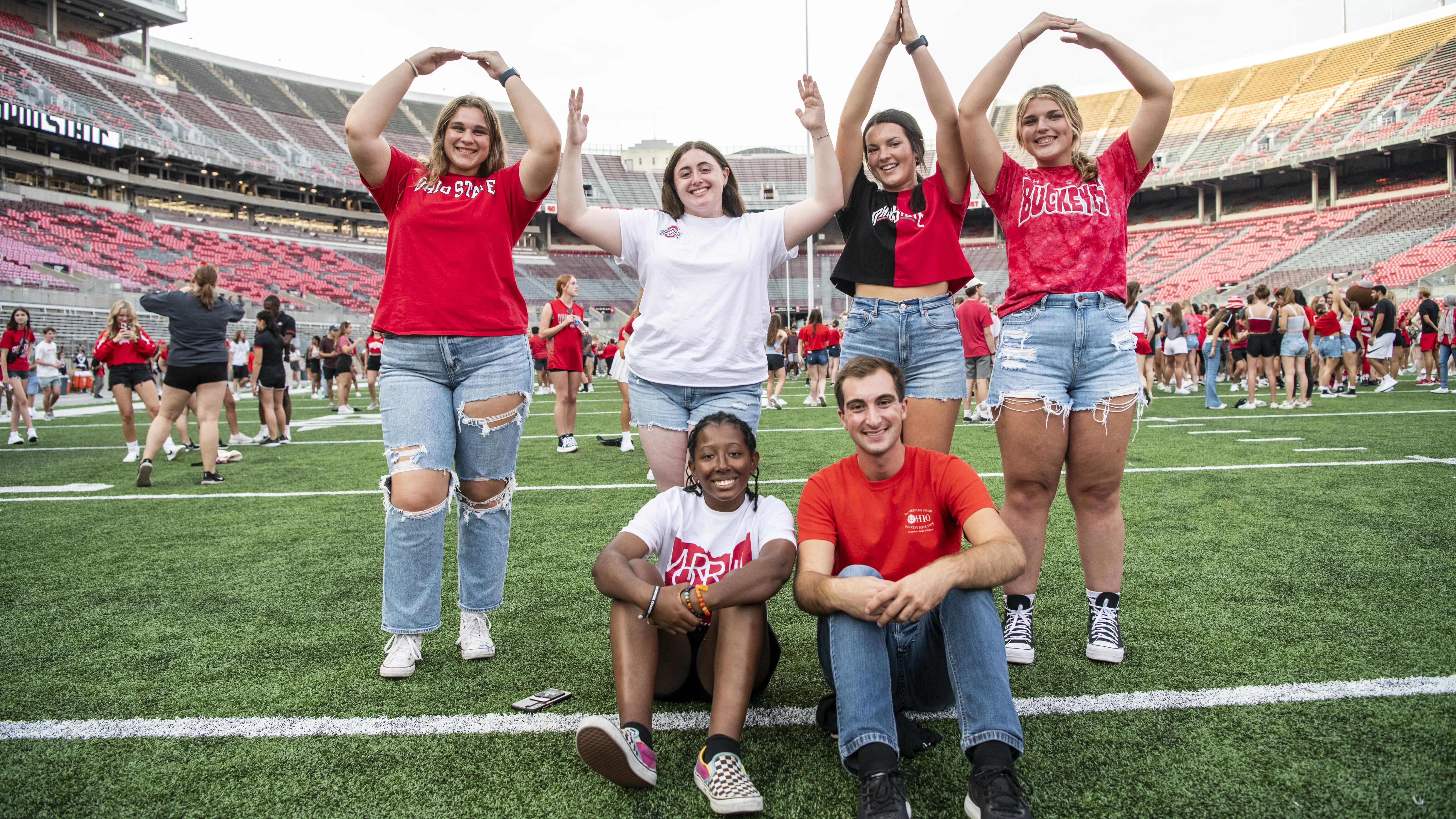 students doing the O-H-I-O pose in Ohio Stadium