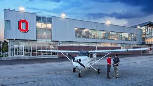 Plane and people in front Ohio State's airport's main building