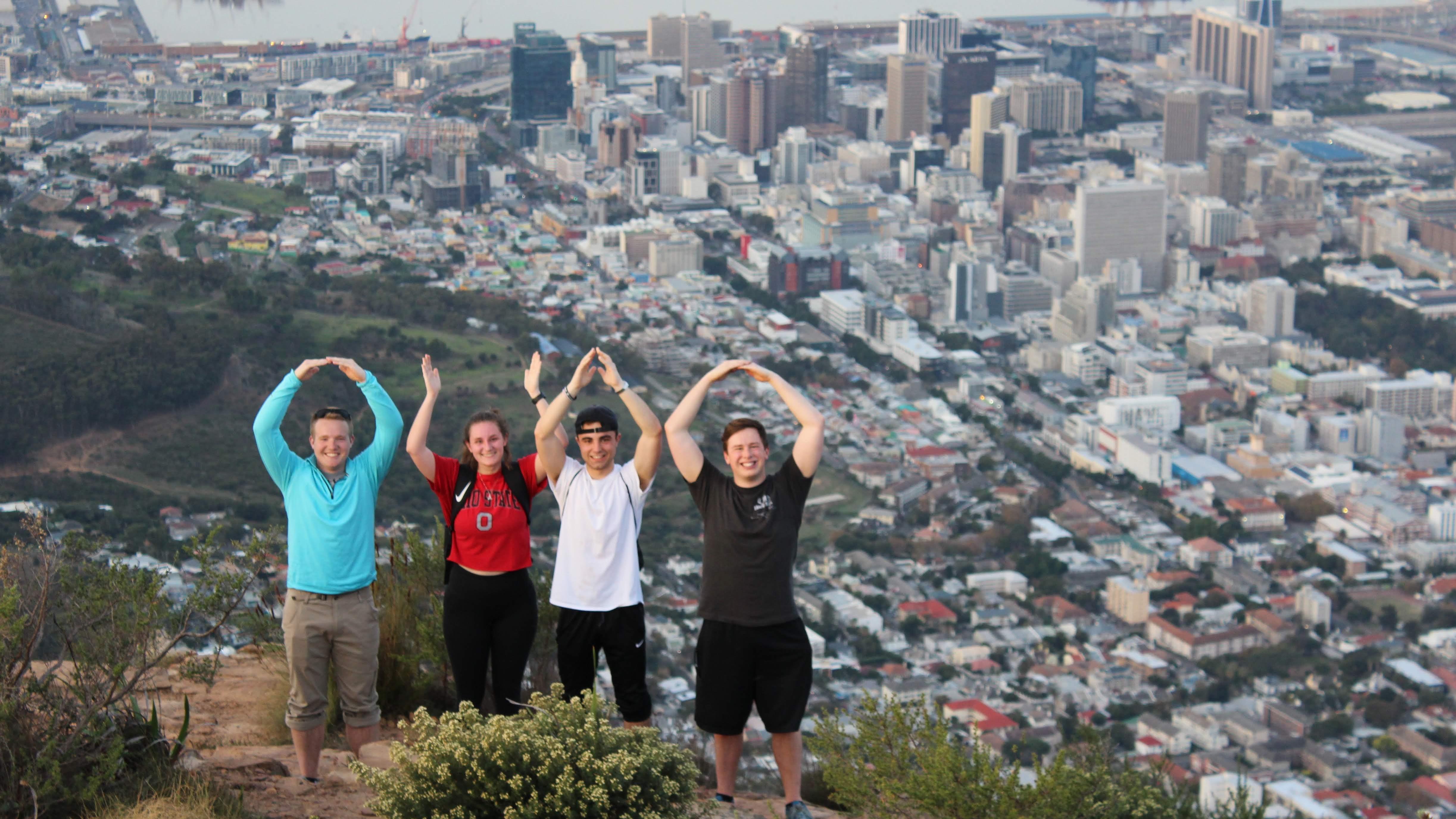 students doing the O-H-I-O pose on a mountain during a study abroad trip