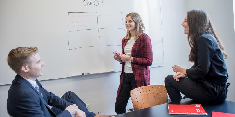 three students working at a whiteboard