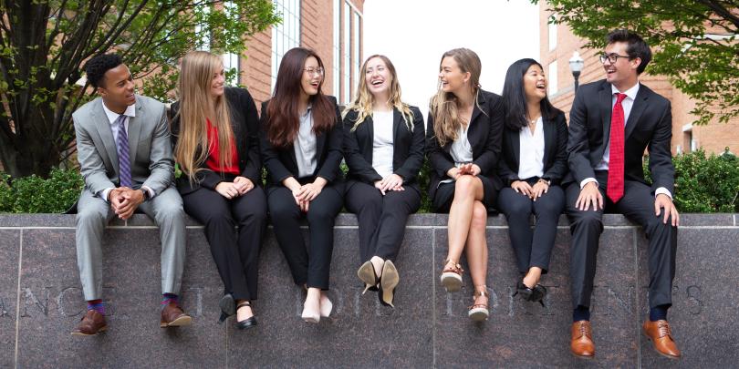 Students in business professional gather and chat together.