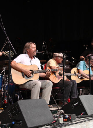 Robert Paquette a fait partie d'un spectacle de groupe pour célébrer le 50e anniversaire du NLFB. Étaient rassemblés des artistes de la première édition, comme Robert Paquette, et des participants fréquents, comme Ian Tamblyn (à droite de Robert). Ils ont interprété des chansons en lien avec le festival. — Photo : Julien Cayouette