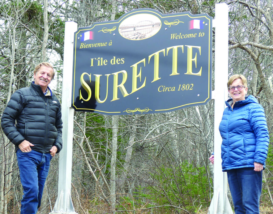 Guy Surette et Anne Surette en avant du nouveau panneau routier à l’Île des Surette. —  Norbert LeBlanc