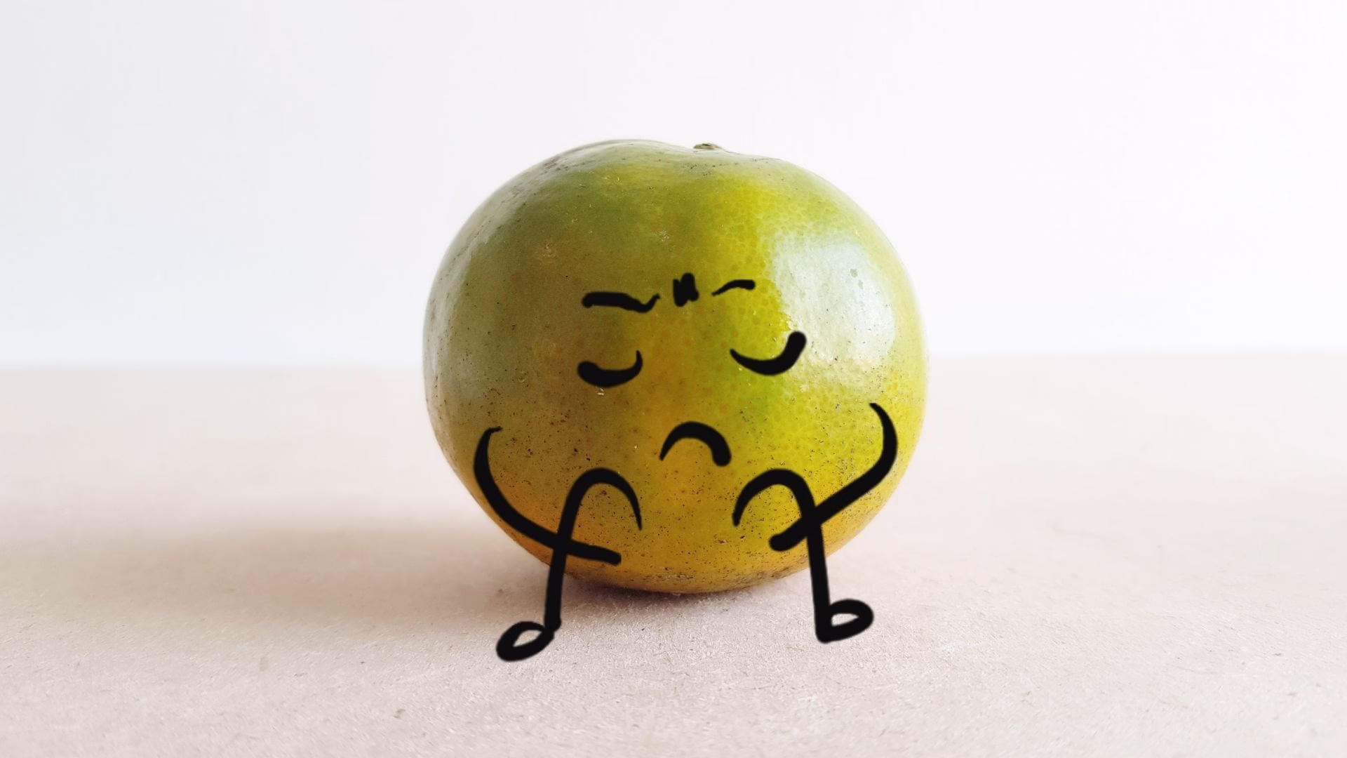 Green-yellow apple with a drawn, cartoon face and stick-figure arms and legs, sitting on a light surface.