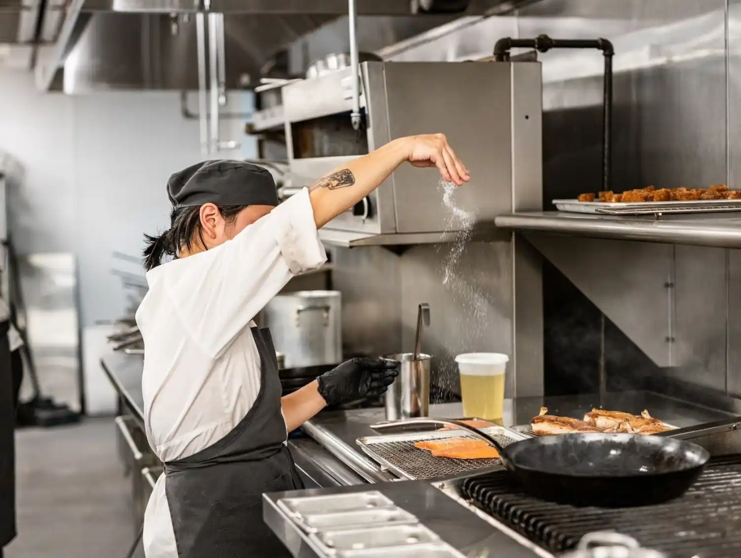 Female Chef Dropping Salt Over Fish