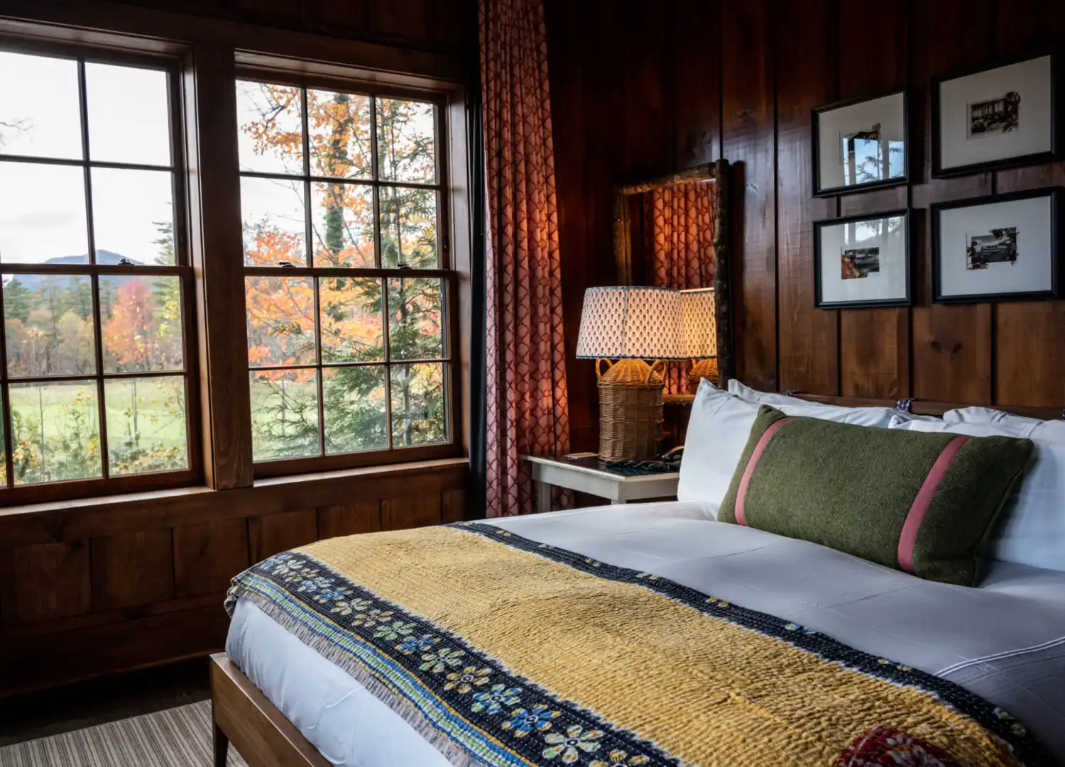 A king sized bed in a warmly lit, wood paneled room