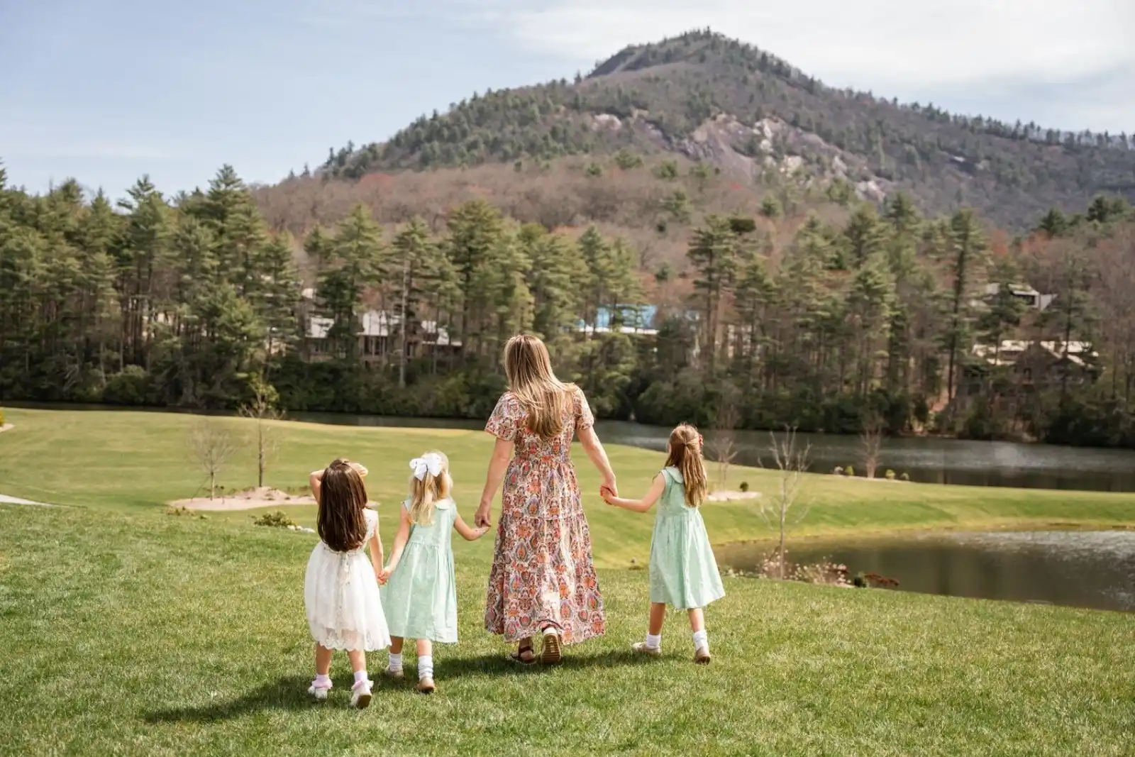 A woman holding hands with her three daughters walking with Rock Mountain in the background A woman holding hands with her three daughters walking with Rock Mountain in the background