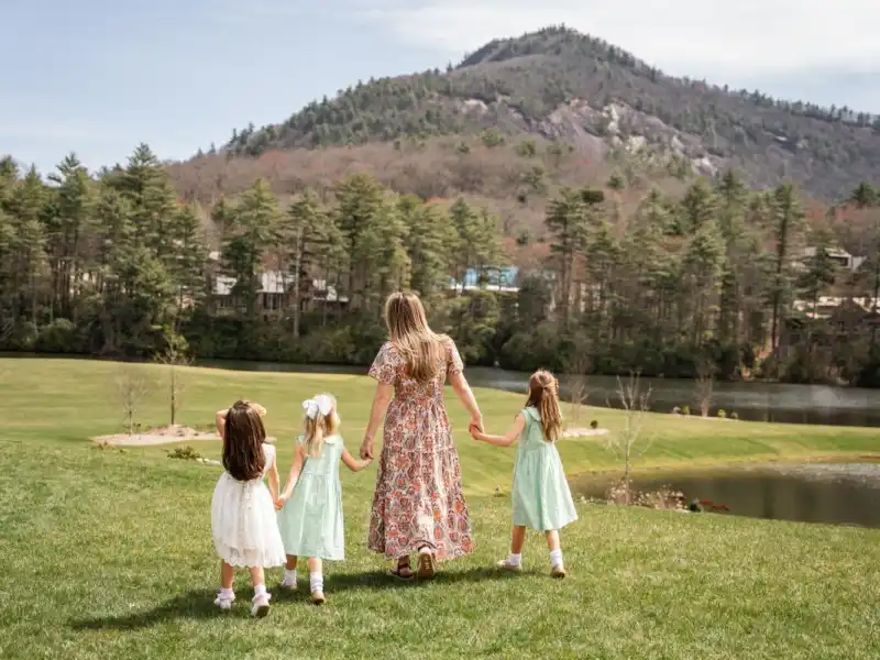 A woman holding hands with her three daughters walking with Rock Mountain in the background