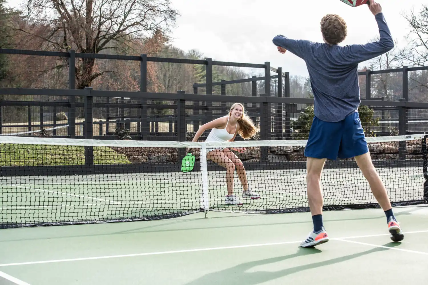 Two people playing pickleball together while smiling