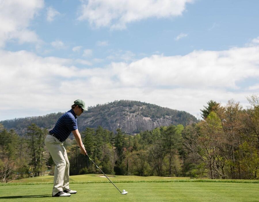 Person golfing with Rock Mountain in the background