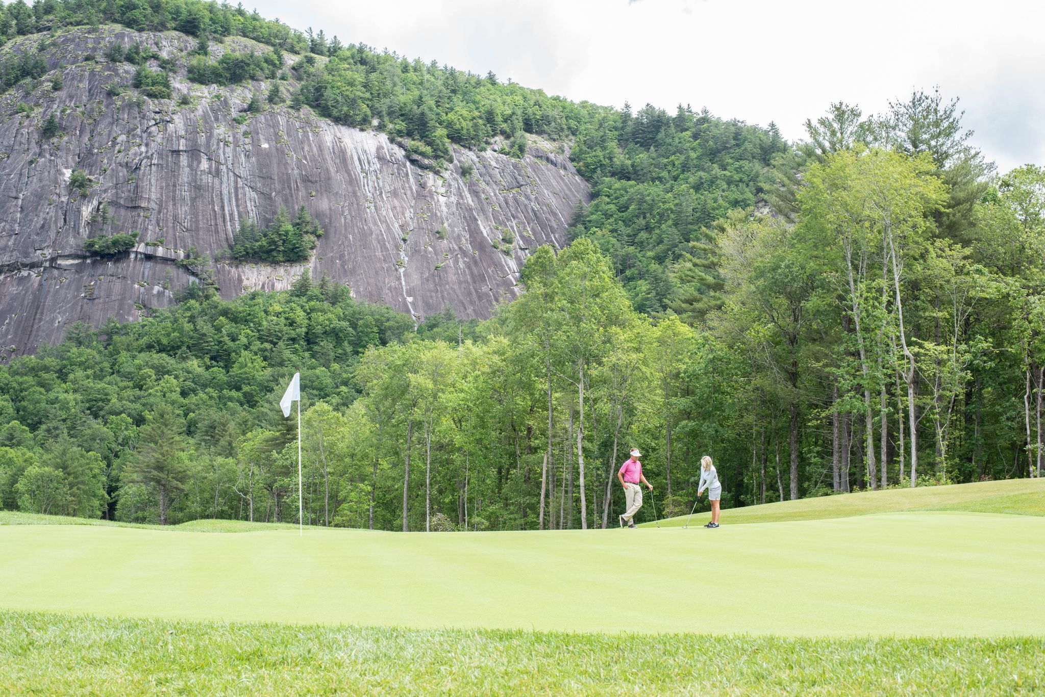 People golfing on golf course with Rock Mountain in background