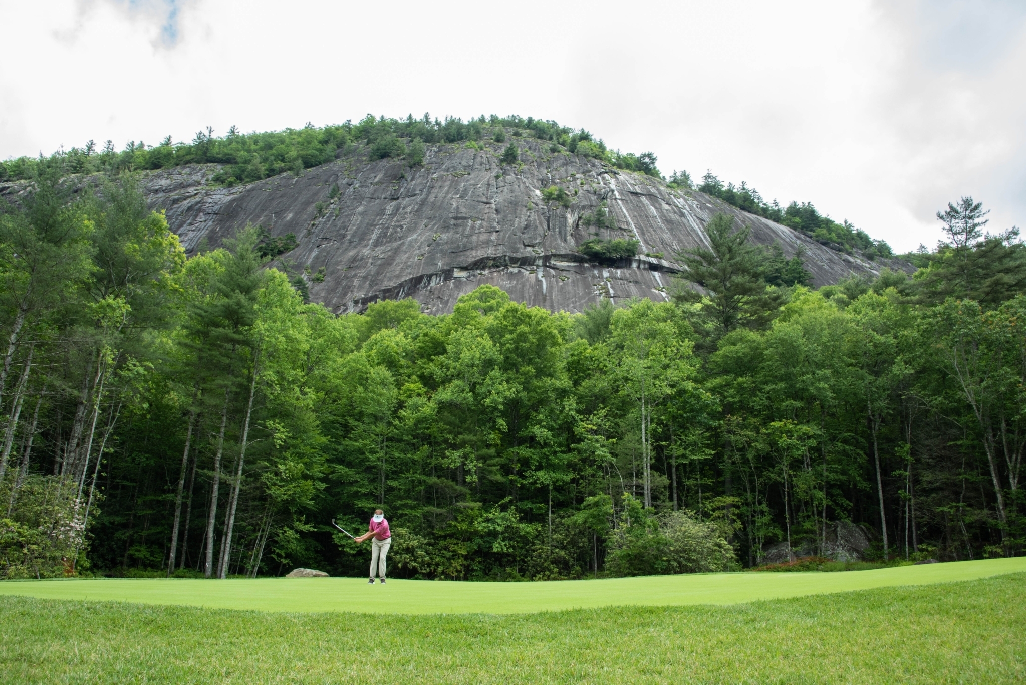 People golfing on golf course with Rock Mountain in background
