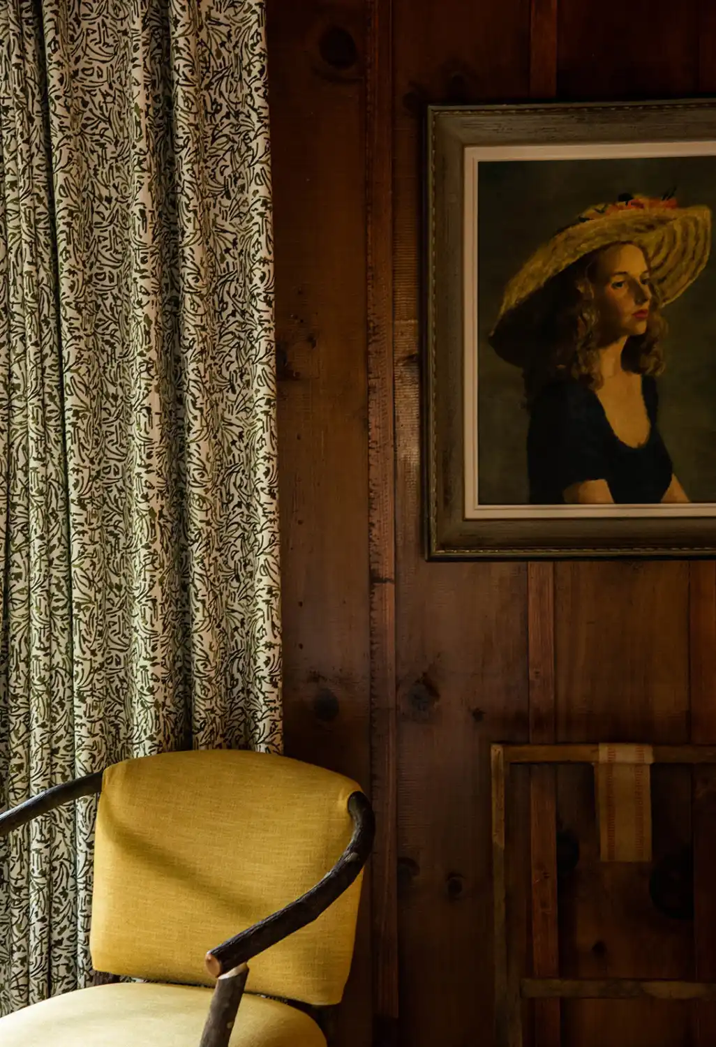 A chair in a corner with a photo of a woman