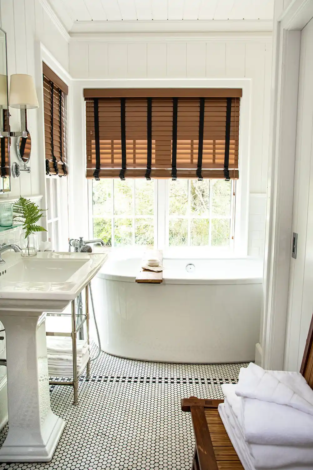 A soaking tub by a window in a warmly lit bathroom