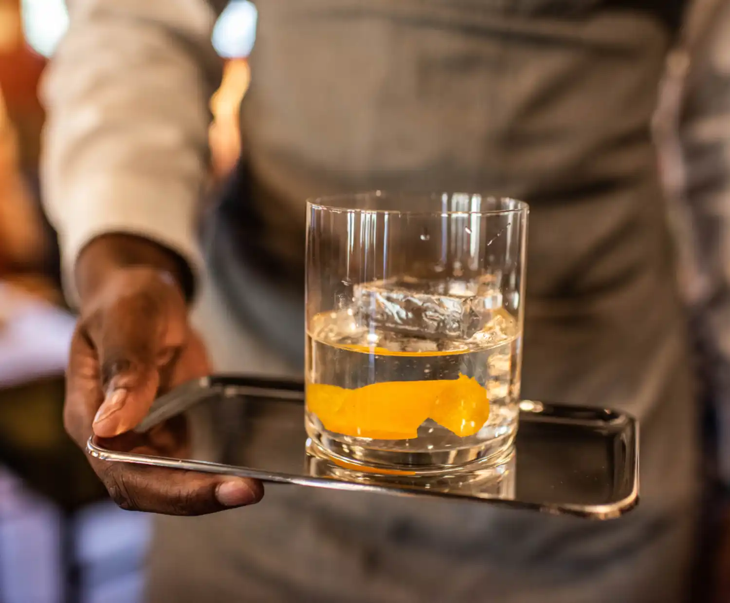 Person serving a cocktail on a tray
