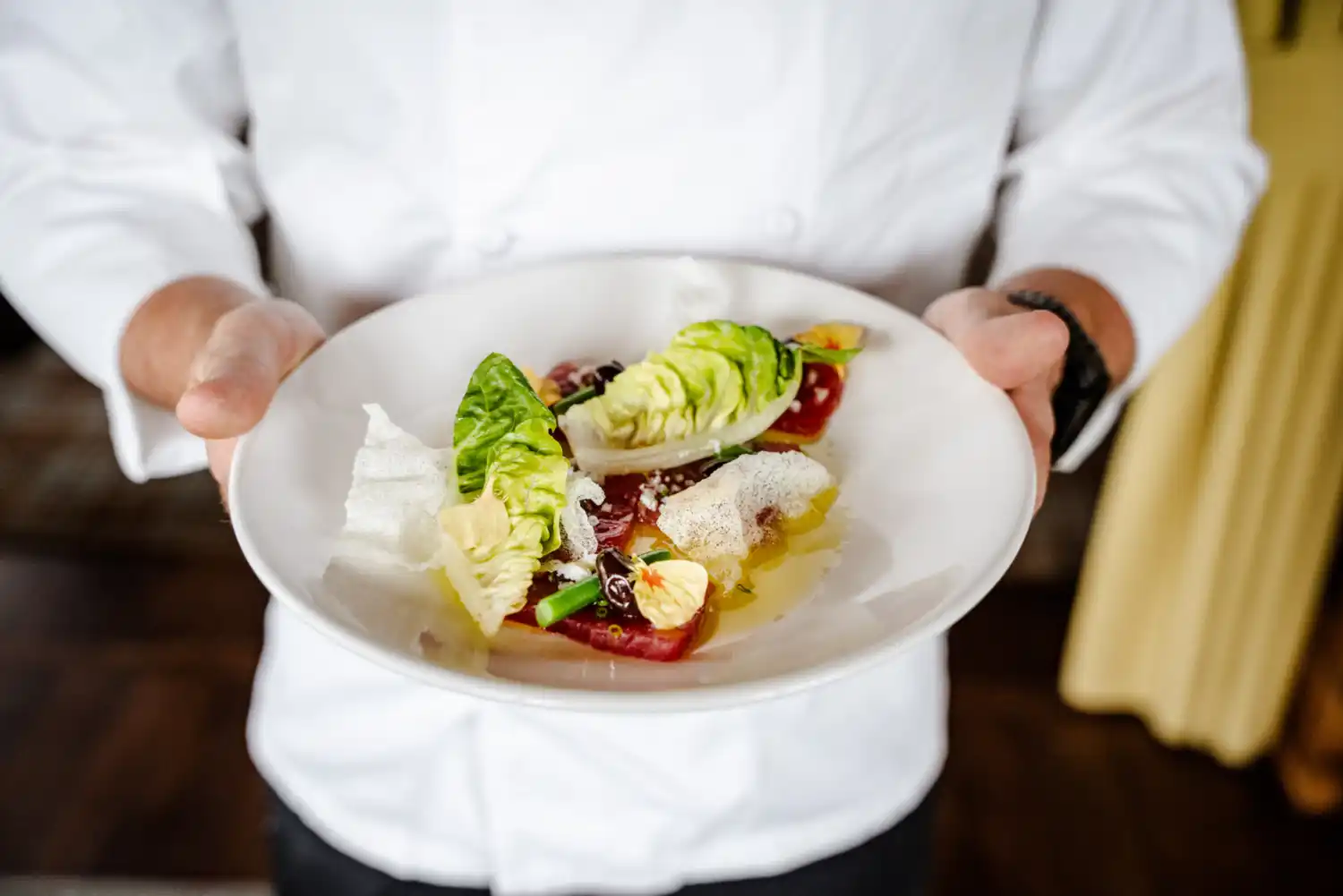 A chef holding a plate of salad