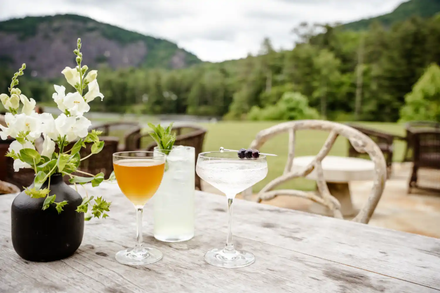 Three cocktails set on an outdoor dining table with Rock Mountain in background