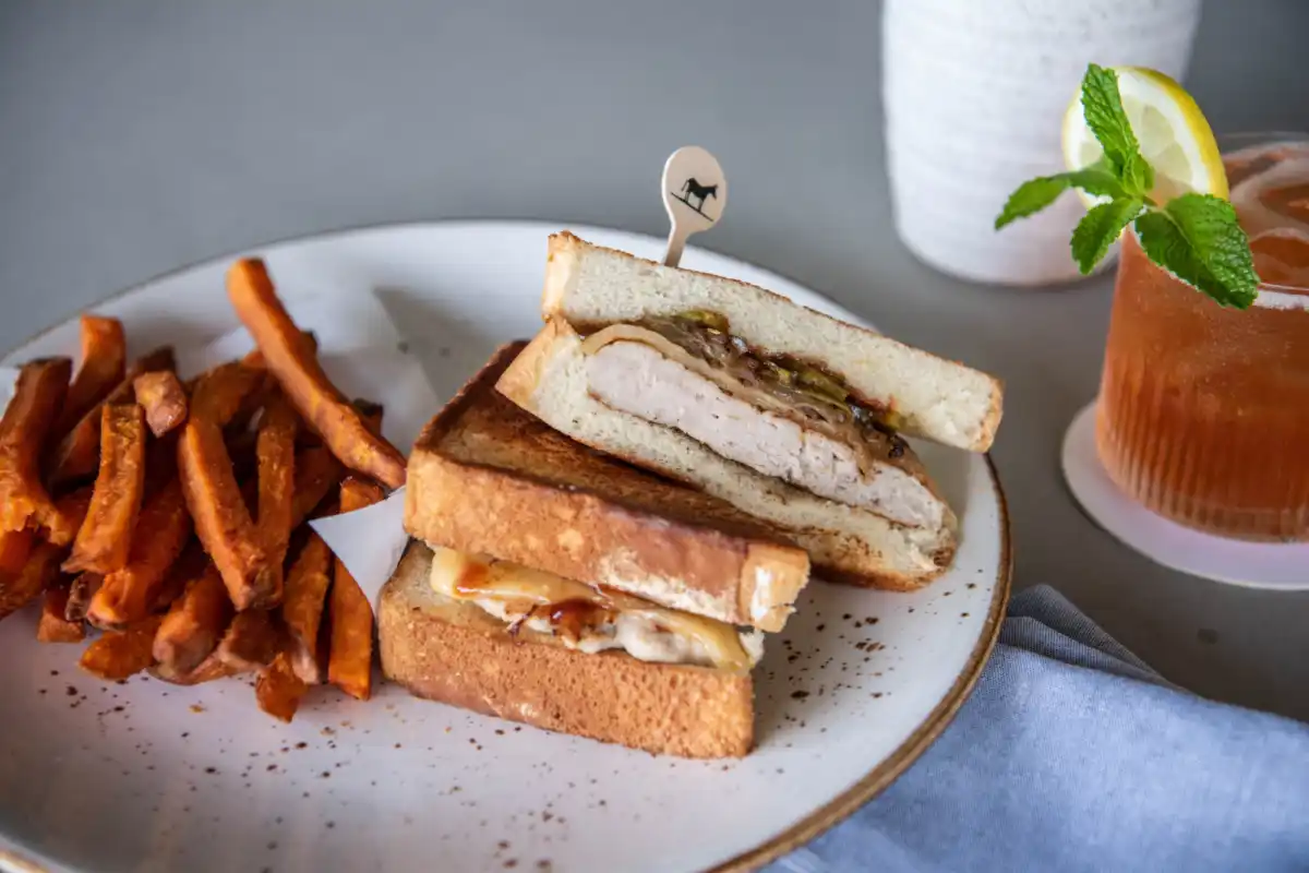 A plated sandwich and fries beside a southern cocktail