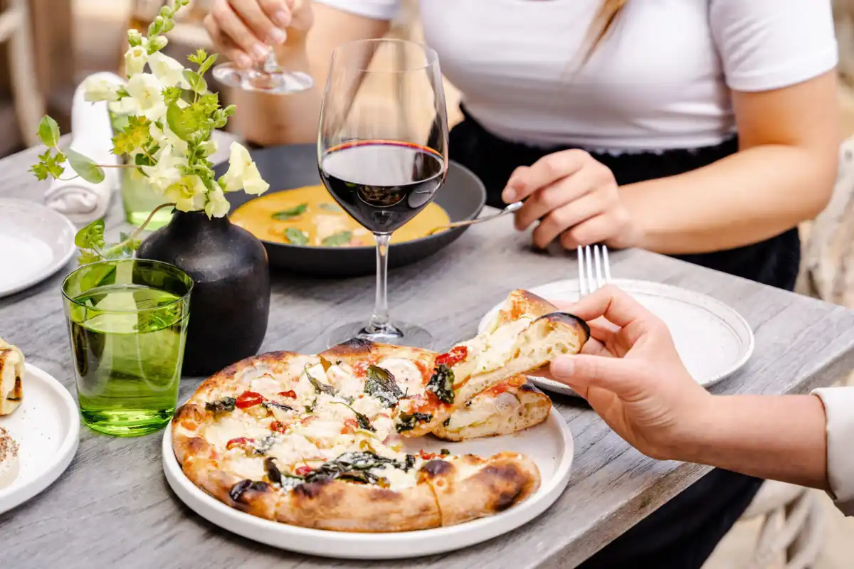 People enjoying flatbread, soup and wine at a dining table