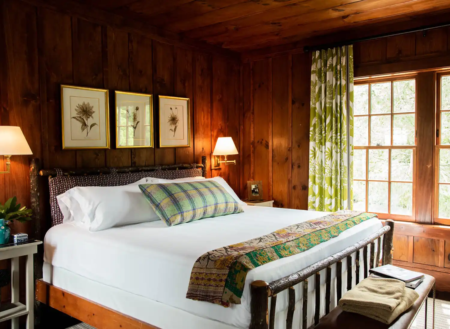 A king sized bed in a warmly lit, wood paneled room