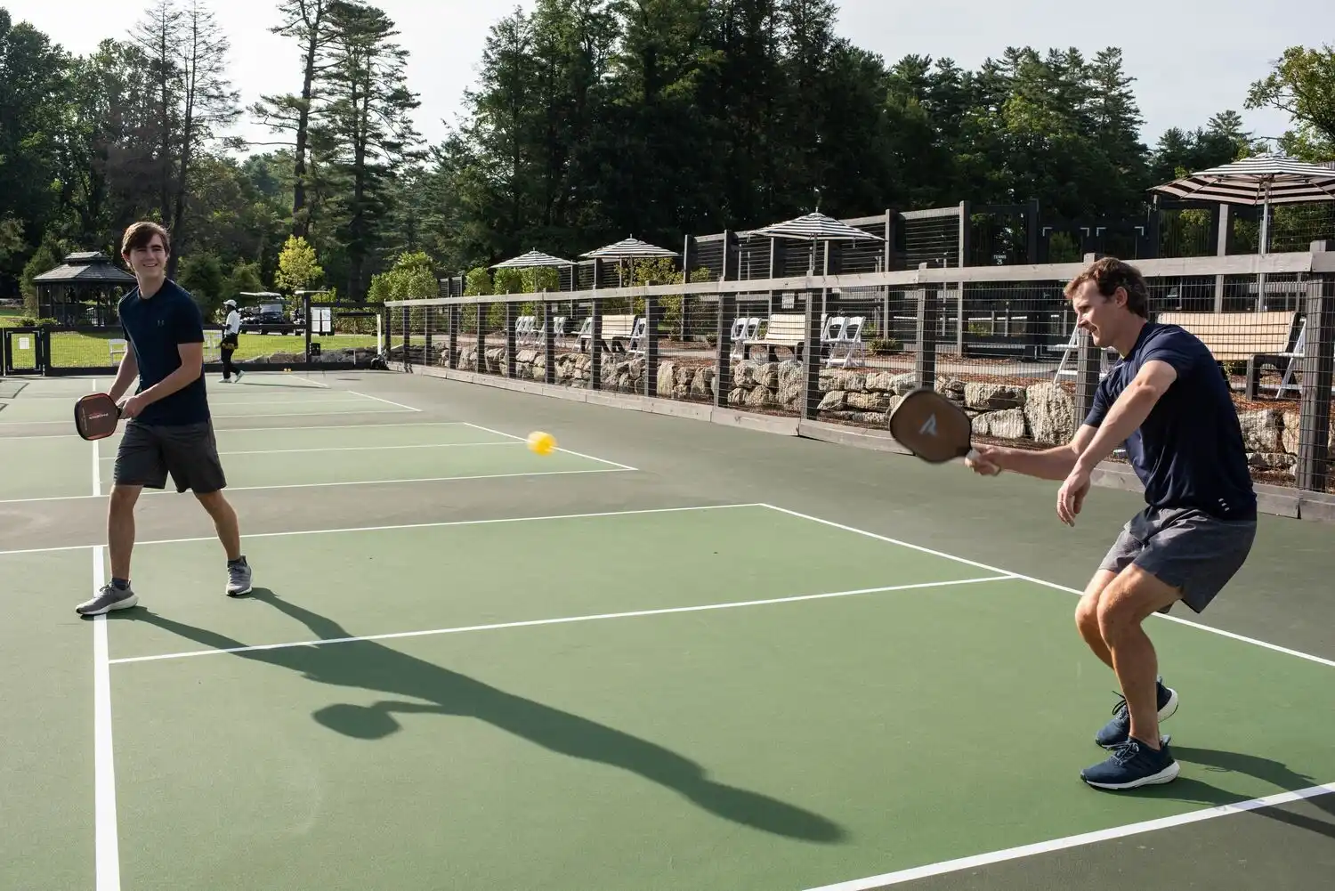 Two men playing pickleball while smiling